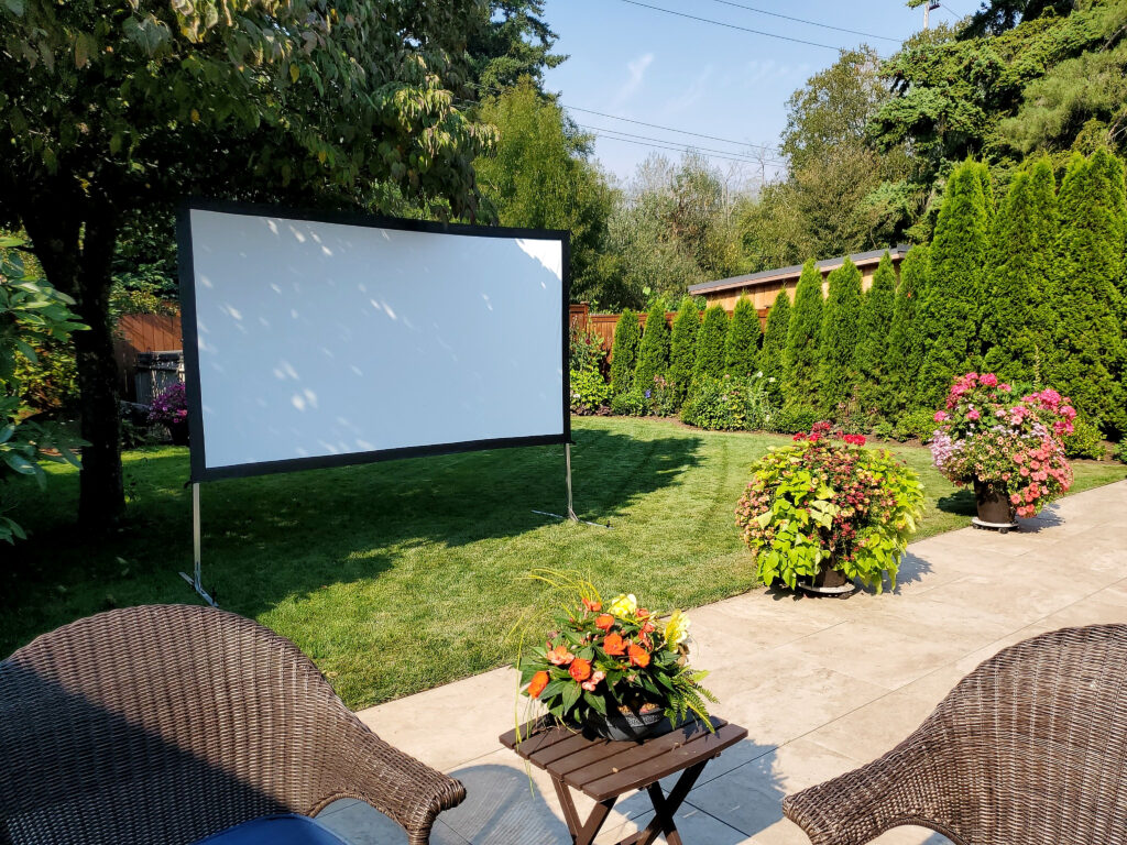 Outdoor movie screen in garden setting.